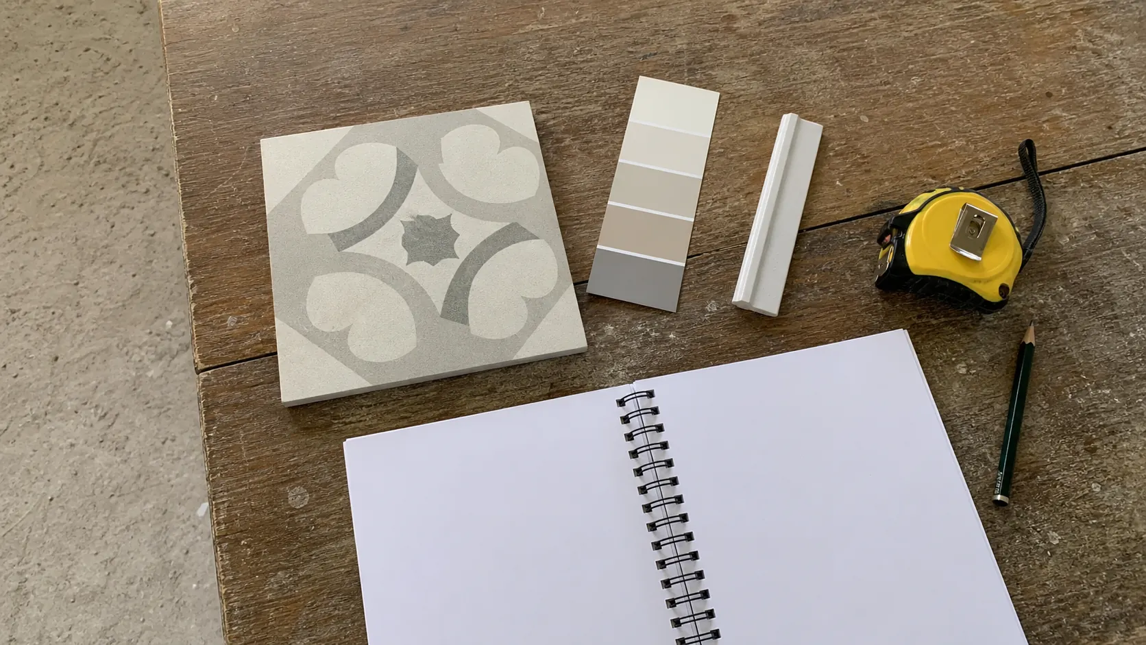 Échantillons de finition et carnet de relevés posés sur une table de chantier.