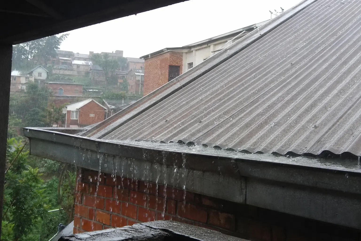 Détail d’une couverture en tôle sous la pluie observée depuis une zone sécurisée.