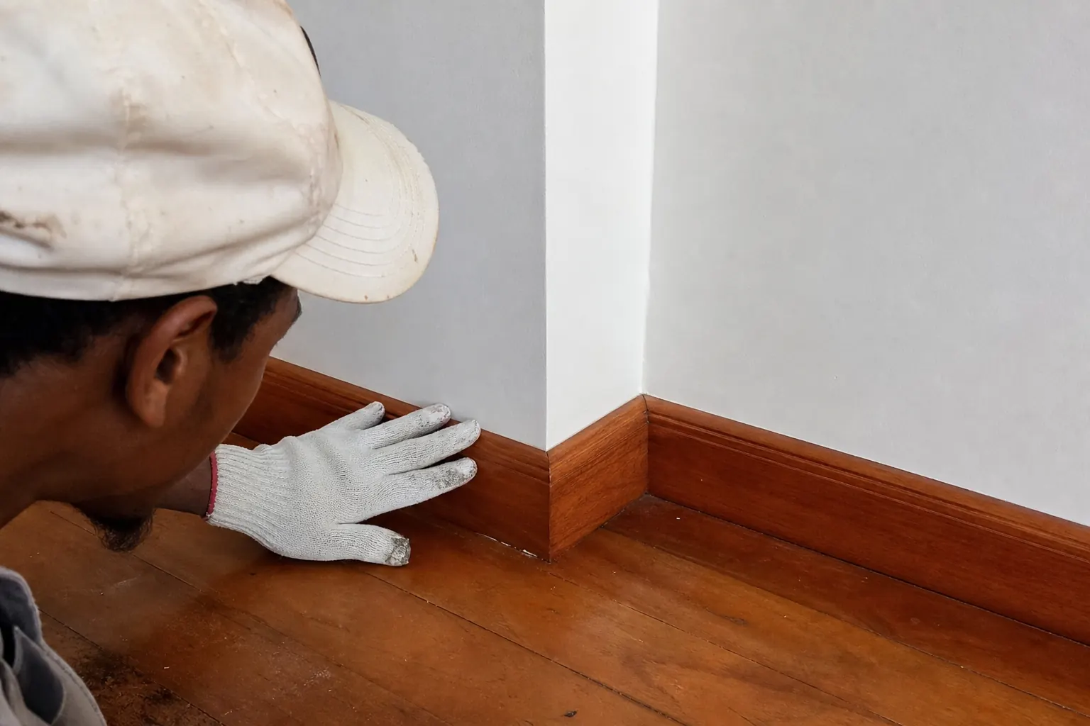 Contrôle de finition entre un mur peint et une plinthe en bois.