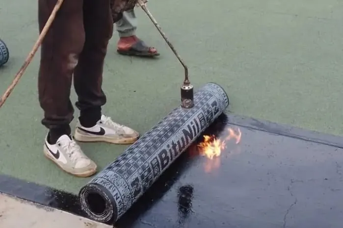 Déroulage et soudure d’une membrane bitumineuse sur une sous-couche noire.