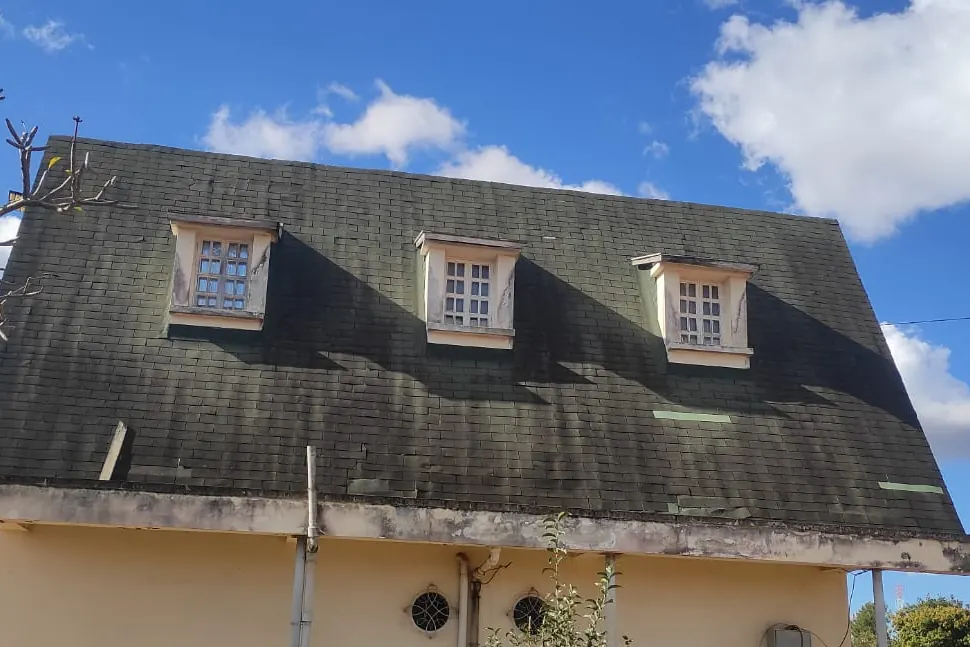Toiture en bardeaux sombres en fin de vie, à rénover.