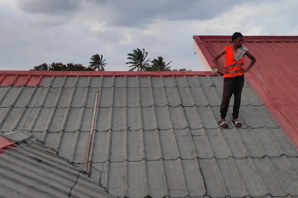 Artisan LAFATRA BTP contrôlant une toiture en tôle recouverte de membrane.